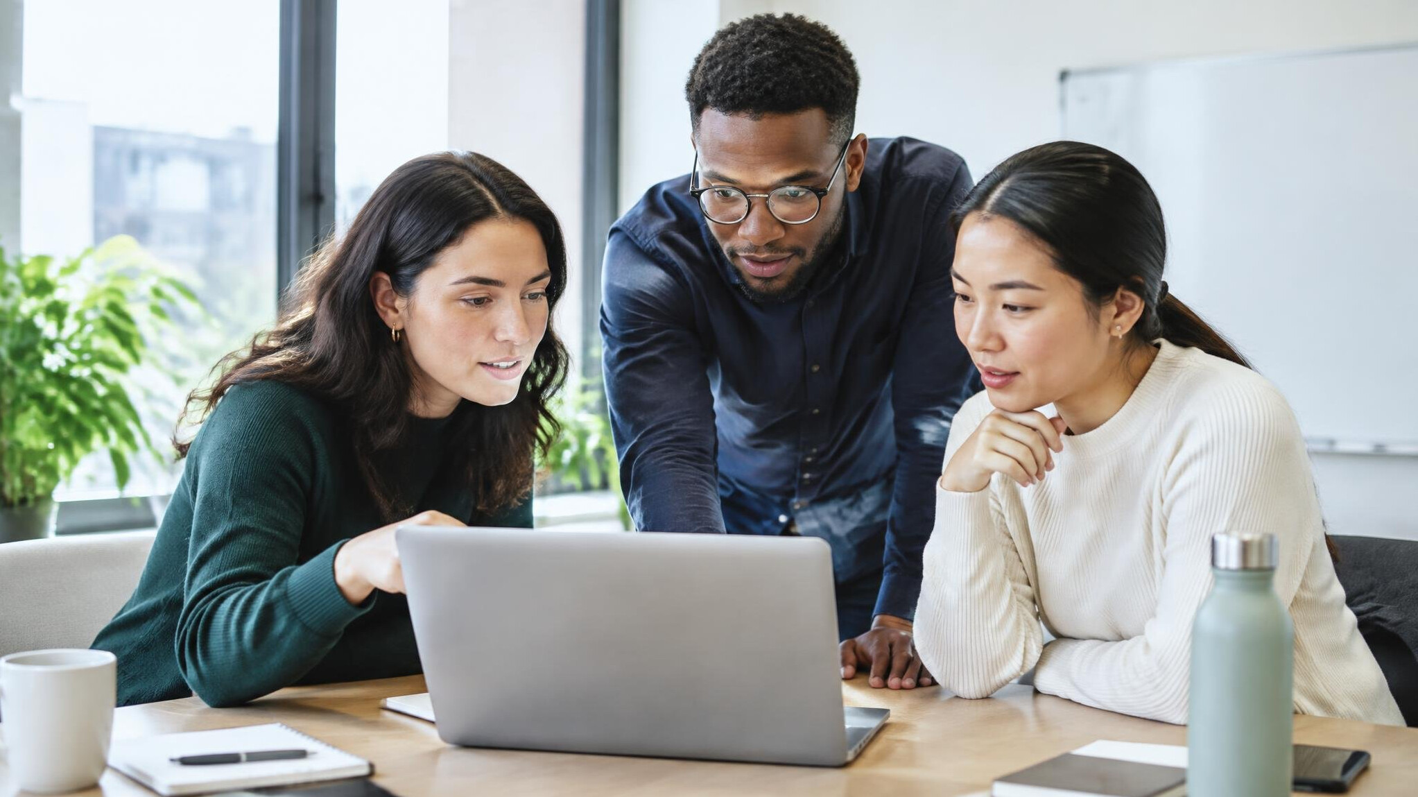 Small team gathered around a laptop in a meeting